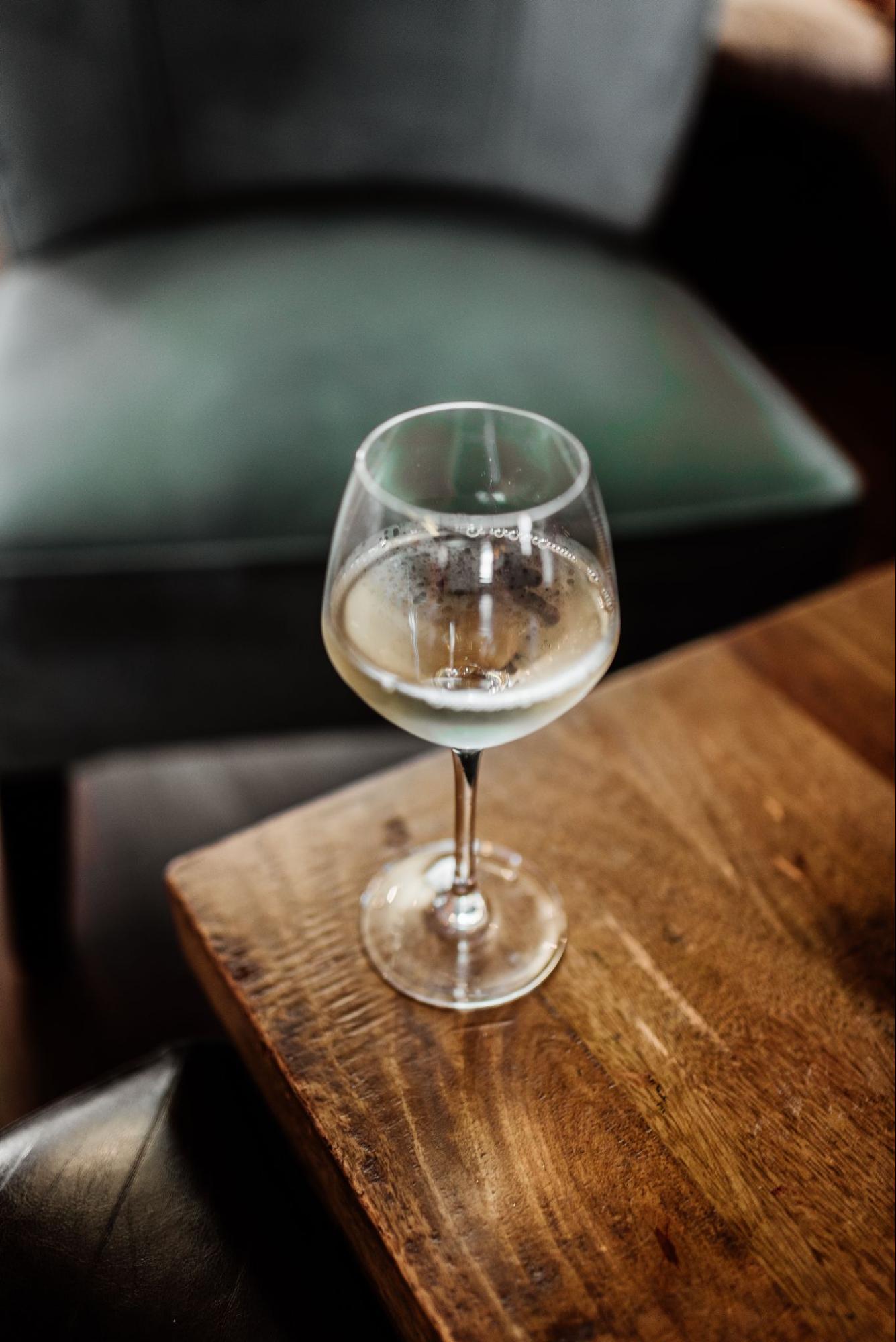 Glass of white wine on the corner of a wooden table