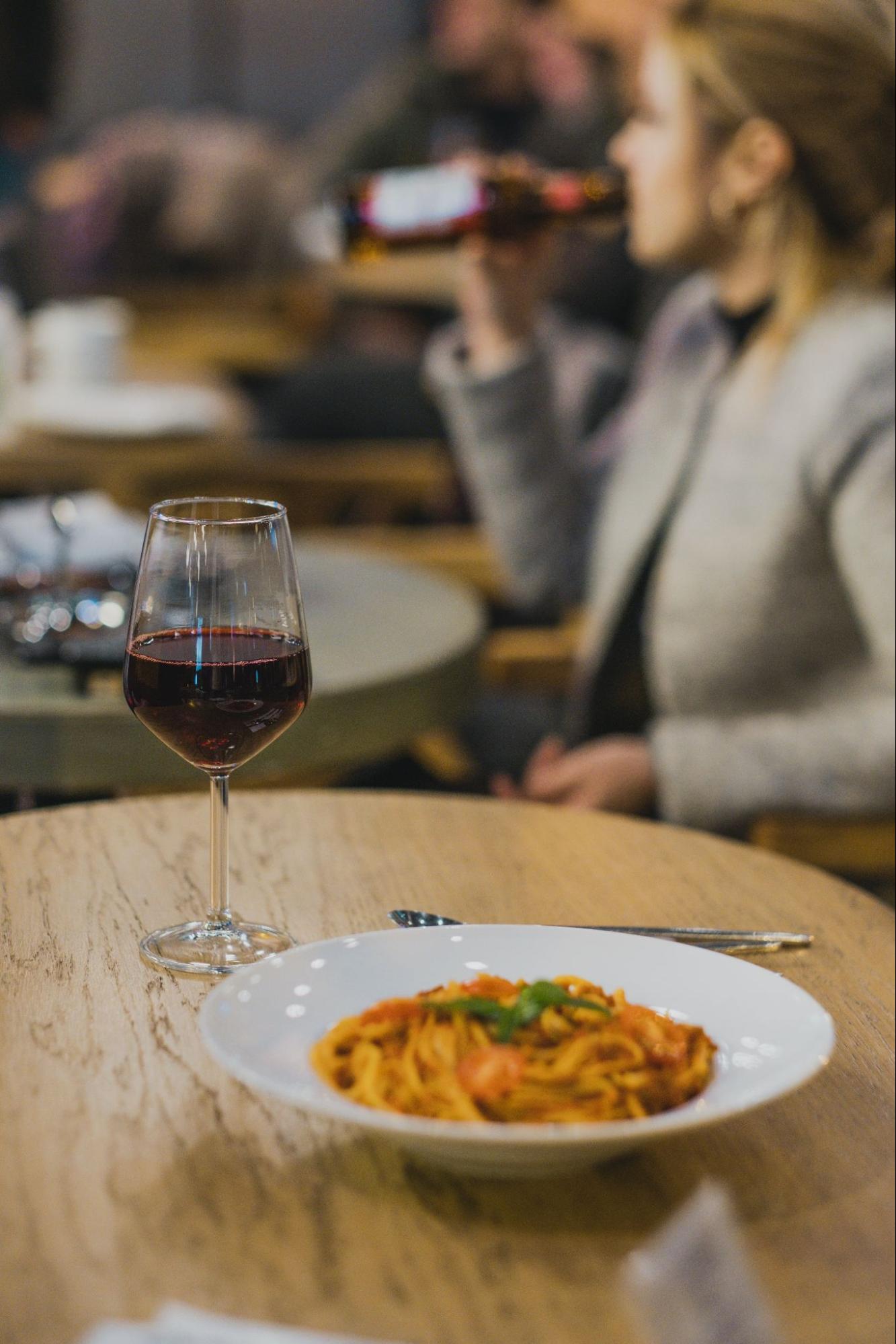 Plate of pasta and a glass of wine on a table