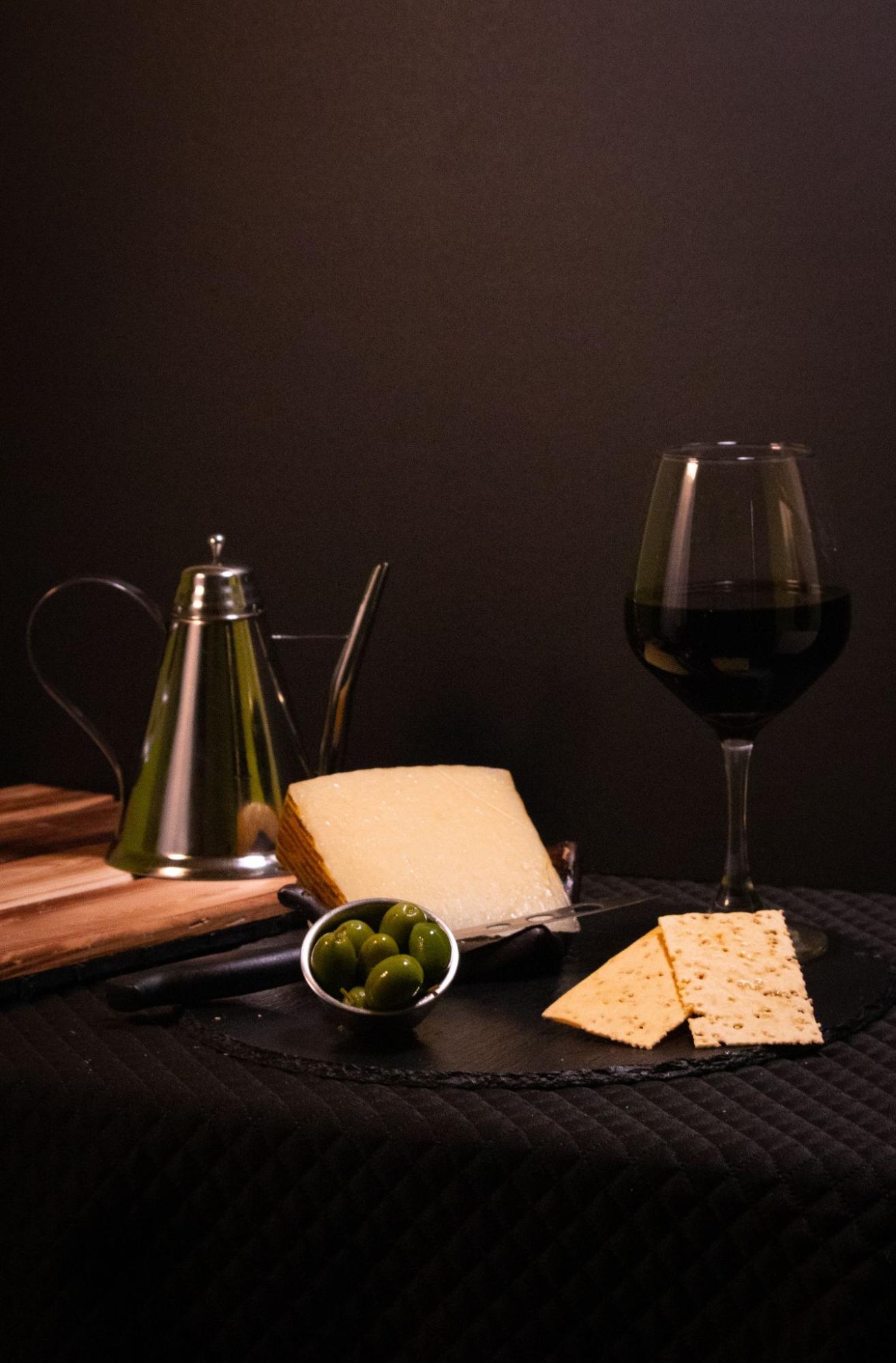 Olives, cheese wedge and crackers with a glass of red wine