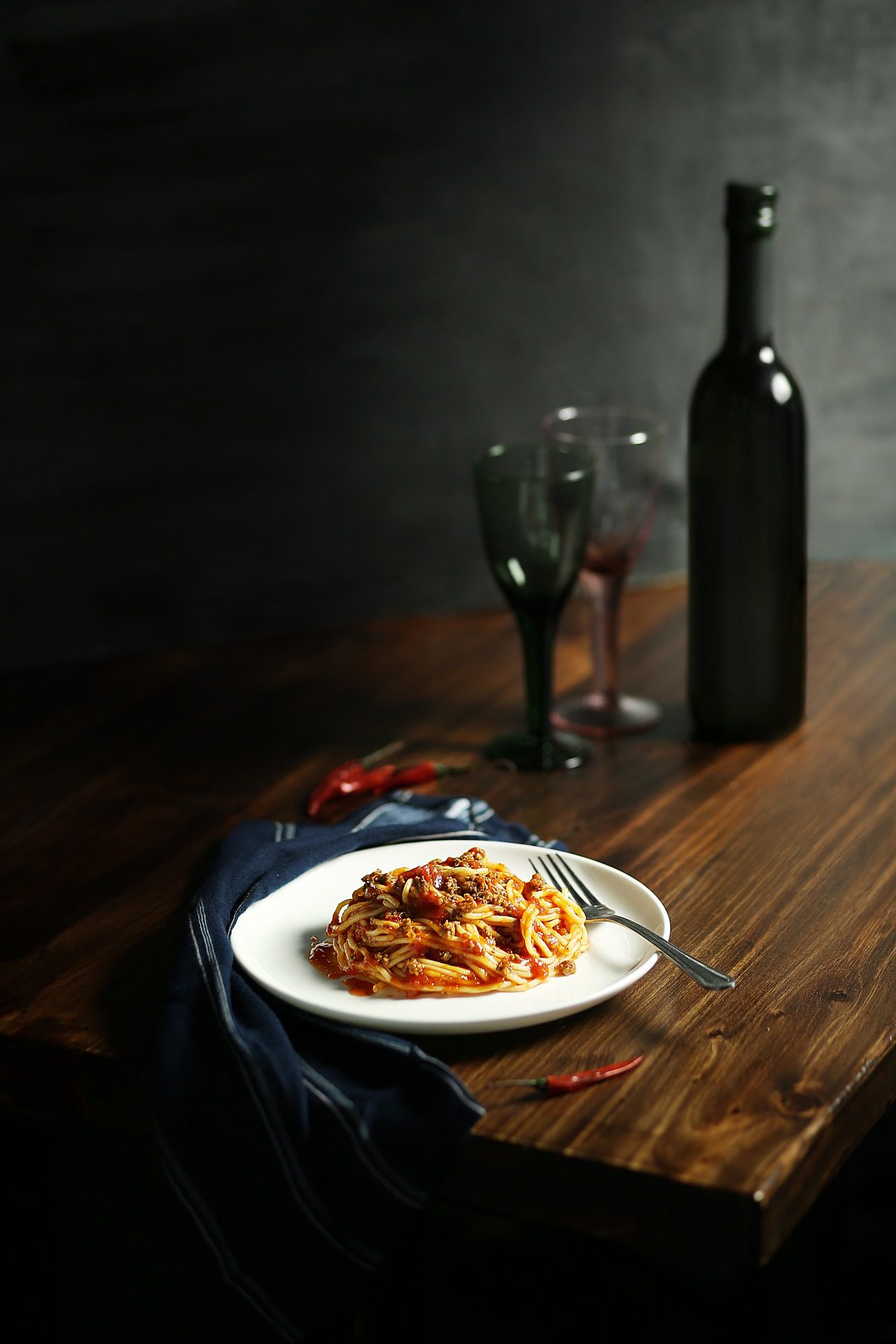 Plate of pasta with a bottle of wine and two glasses