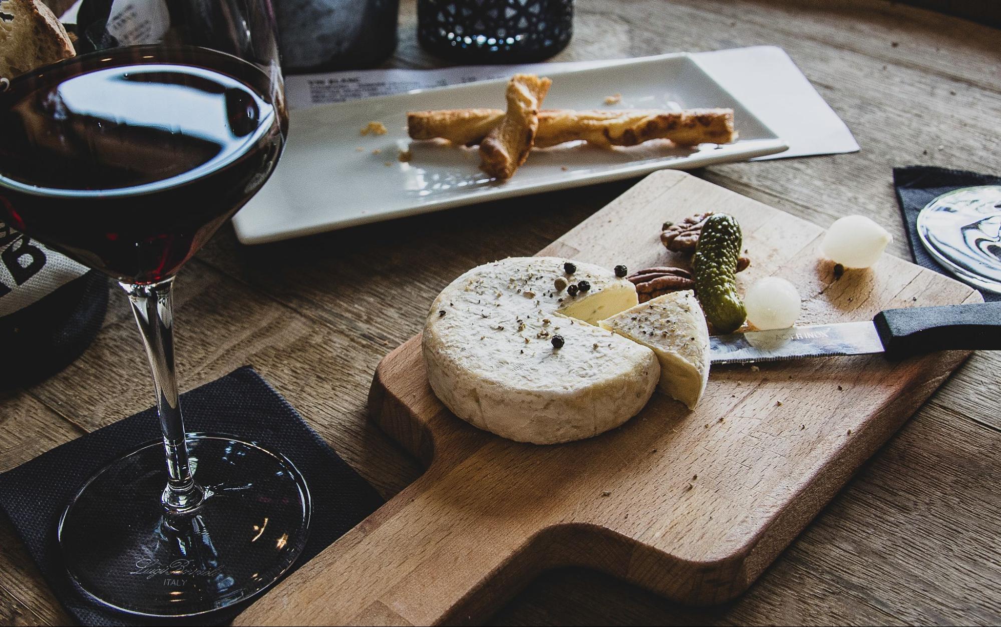 Cheese wheel on a board with a glass of wine beside